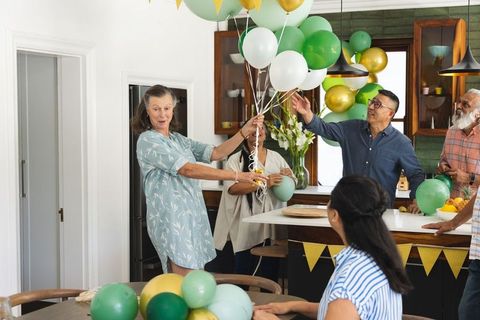 Multigenerational family decorating kitchen with green gold balloons celebrating together