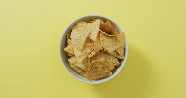 Close up of nachos in a bowl with copy space on yellow surface. food and snack concept