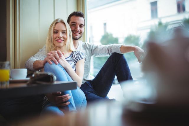 Portrait of smiling couple sitting with arms around in cafÃ©