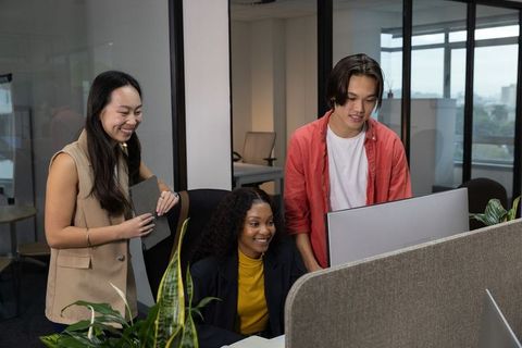 Multicultural team collaborating at modern open-plan workstation with monitor