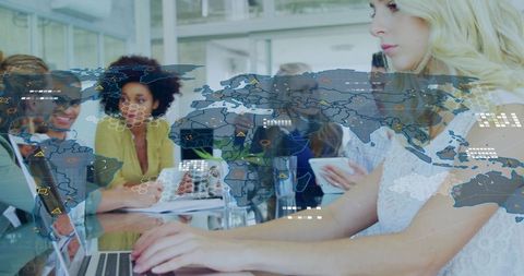 Typing woman working on laptop with translucent global data overlay in collaborative office