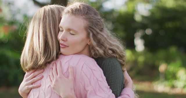 Women sharing a heartfelt hug in an outdoor garden setting. Suitable for themes of friendship, support, love, emotional connections, and positive relationships. Ideal for use in blogs, social media posts, promotional materials, and wellness content.