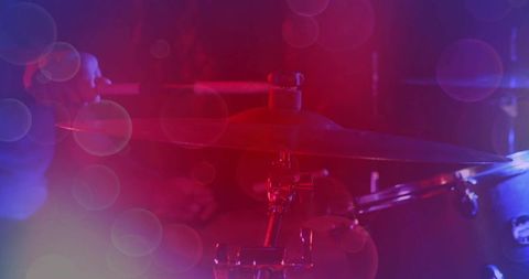 Glowing crash cymbal catching stage lights close-up with bokeh and drum hardware