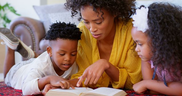 Mother spending quality time reading Bible with young son and daughter. Encourages family bonding, spiritual growth and education at home. Useful for parenting blogs, educational materials, religious publications, and family lifestyle content.