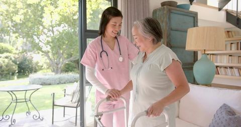Caregiver supporting senior woman using walker in sunlit home care scene with stethoscope