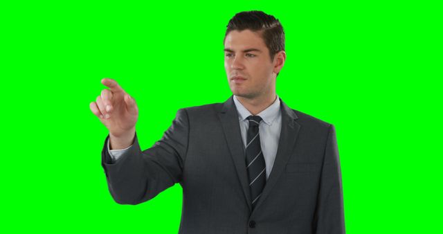 Businessman wearing a gray suit pointing at virtual interface on green screen background. Perfect for presentations, technology demonstrations, or business-related marketing materials. Useful for corporate websites, advertisements, or digital content featuring business concepts.