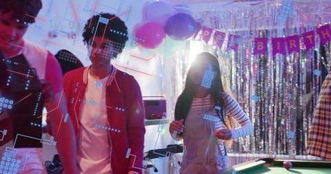 Teens celebrating birthday by pool table with neon lights, balloons and fringe banner
