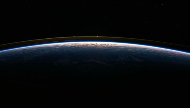 Curving earth horizon revealing layered atmosphere and airglow at twilight from low orbit