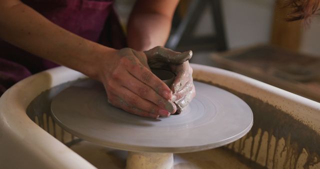 Close up view of female potter creating pottery on potters wheel at pottery studio. hygiene and social distancing in the pottery studio during coronavirus covid 19 pandemic.
