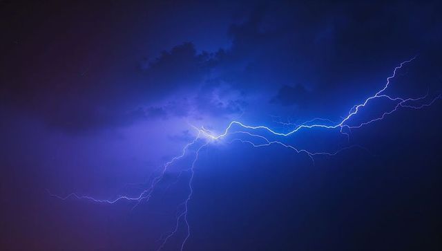 Dramatic blue lightning electryfing purple night sky