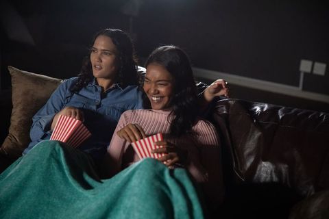 Friends enjoying movie night at home sharing popcorn and laughter