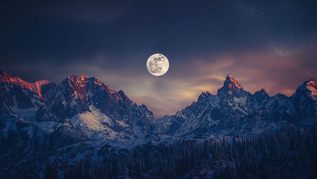 Full moon over snowy peaks in twilight alpine vista