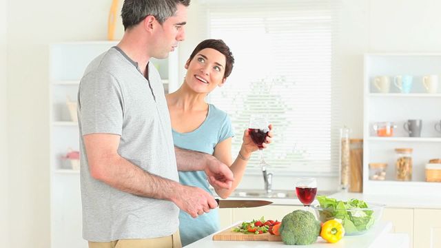 Couple enjoying time together in modern kitchen with fresh vegetables on counter, promoting healthy living and relationships. Ideal for lifestyle and home advertisements, cooking shows, or articles on healthy eating, family life, and relationship tips.