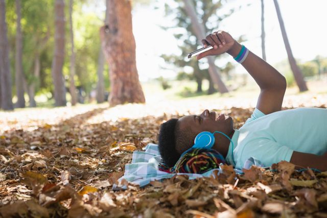 Young Man Relaxing in Park with Mobile Phone and Headphones - Download Free Stock Photos Pikwizard.com