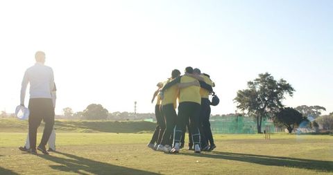 Cricket team huddling on grass for pre-match strategy