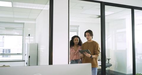 Diverse coworkers analyzing tablet in modern office setting