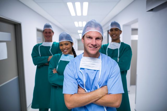 Portrait of nurse and surgeons standing with arms crossed in corridor of hospital