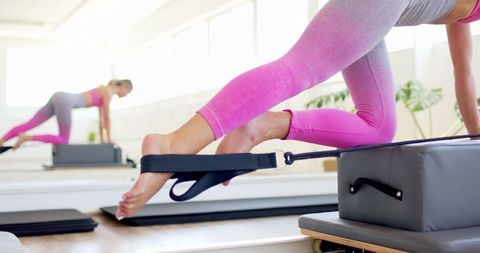 Woman Practicing Pilates on Reformer Machine in Fitness Studio