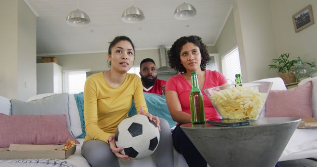 Diverse tense female and male friends watching football on tv at home, in slow motion. Free time, friendship and lifestyle concept.