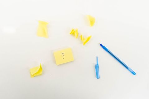 Blue pen and yellow sticky notes on white desk