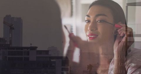 Woman applying mascara in urban setting