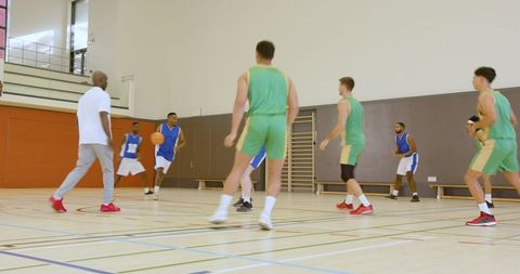 Coach Guiding Basketball Players in Intense Indoor Training Session