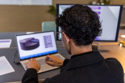 Asian male analyzing pie chart on laptop at modern office workstation