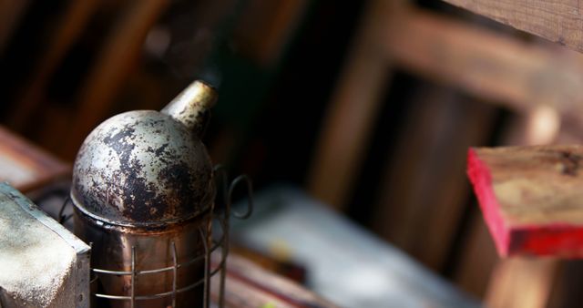 Focus on an old, smoky beekeeping smoker shows it in use on a farm. Image has rustic, vintage feel, making it ideal for agricultural or apiculture themes. Perfect for illustrating farming practices, beekeeping equipment, rural life, or history of beekeeping.