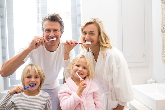 Family brushing teeth together in bathroom, promoting dental hygiene and healthy habits. Ideal for use in advertisements for dental products, family health campaigns, or articles about morning routines and family bonding.