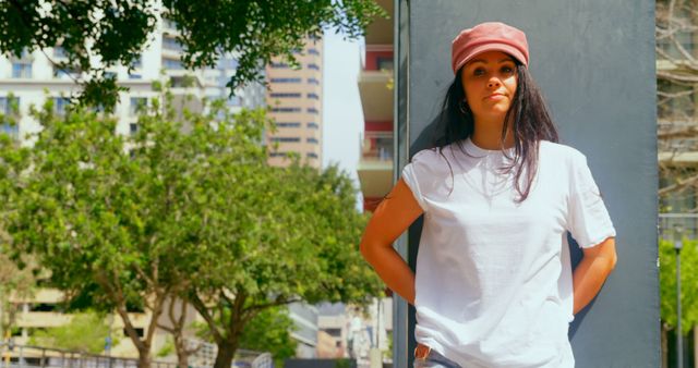 A young African American woman stands confidently in an urban setting, with copy space. Her casual attire and relaxed posture suggest a laid-back, sunny day in the city.
