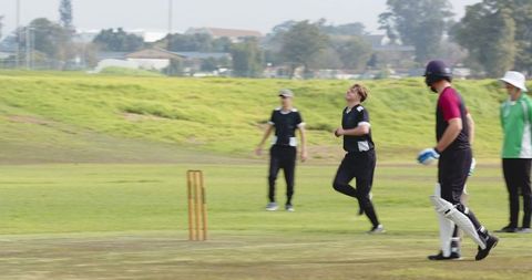 Cricketer sprinting on suburban grass field during dynamic match