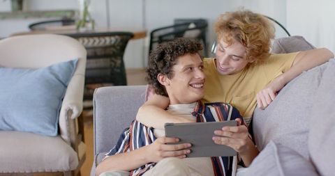 Joyful Diverse Couple Relaxing Together with Tablet at Home