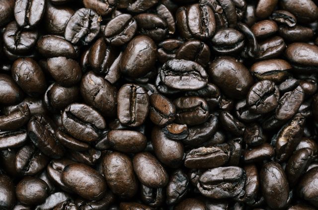 Close-up image showcasing the rich color and texture of roasted coffee beans. Ideal for use in branding, food packaging, promotional materials, articles focused on coffee culture, cafes, and coffee-related websites.