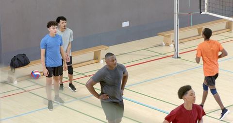 Multiracial young men practicing indoor volleyball on gym court during team training