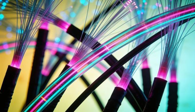 Glowing fiber optic cables emitting neon magenta and cyan light abstract macro