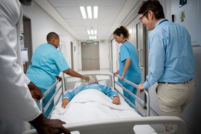 Medical team transporting patient on hospital bed through corridor. Diverse group of doctors and nurses working together in emergency situation. Useful for healthcare, medical services, teamwork, and hospital care themes.
