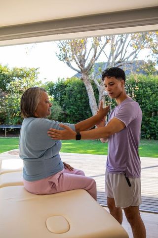 Senior woman rehabilitation exercise with therapist on outdoor patio