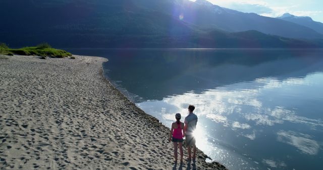 Couple Enjoying Scenic Beach Walk by Calm Lake - Download Free Stock Images Pikwizard.com