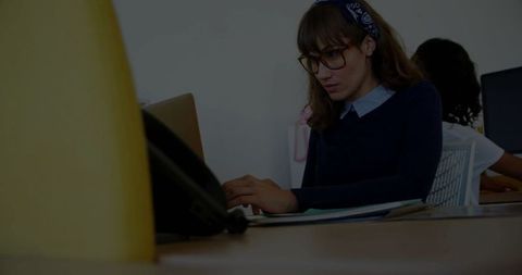Focused woman typing on laptop in modern open-plan office