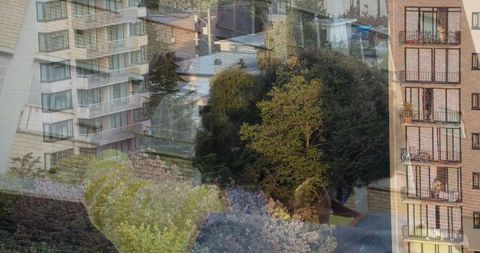 Woman behind glass overlooking urban apartments and trees
