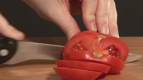 Close-Up of Hands Chopping Ripe Tomato Slices