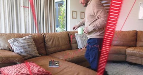 Man holding green mug stepping on brown leather sectional with red motion streaks