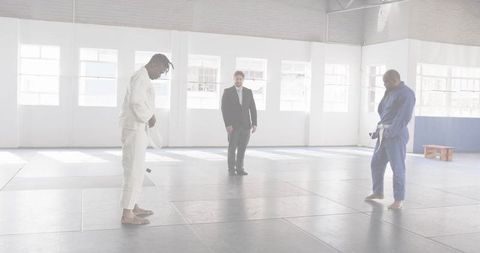 Bowing Martial Artists Preparing for Match on Tatami Mats in Bright Minimal Dojo