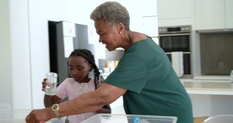 Grandmother and granddaughter sorting jars and recycling in modern kitchen