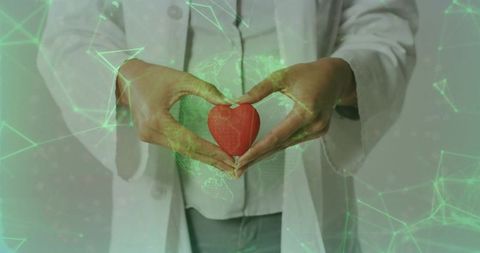 Female doctor holding red heart with digital network overlay for telemedicine cardiac care
