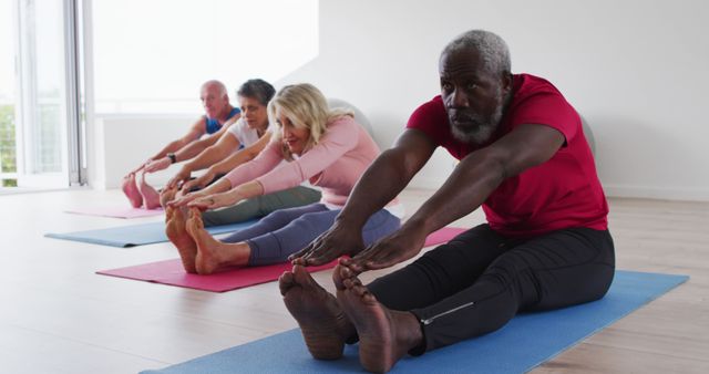 Mature adults stretching on yoga mats in light-filled studio, promoting fitness, flexibility, and community health.