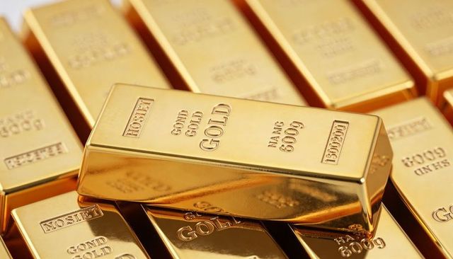 Stacked gold bars reflecting warm light showing embossed purity stamps