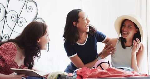 Diverse Young Women Sharing Laughter While Packing for Vacation