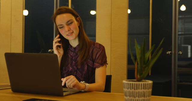 Businesswoman Making Phone Call While Working on Laptop in Modern Office - Download Free Stock Images Pikwizard.com