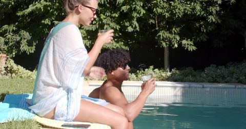Diverse Couple Relaxing by Pool with Refreshing Drinks
